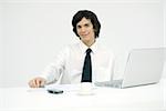 Young professional sitting at desk, smiling at camera