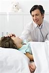 Girl lying on examination table, doctor touching her forehead