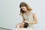 Little boy resting head on mother's lap, woman stroking child's hair