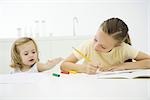 Mädchen Hausaufgaben am Tisch, jüngere Schwester erreichen für Buntstifte