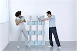 Man and woman joking, fighting over DVDs on shelf