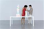 Couple standing beside table stacked with boxes, man giving woman a gift