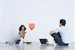 Man and woman playing spin the bottle with laptop computers