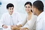 Young professionals sitting at table, focus on woman in center