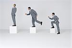Identical businessmen climbing gradually larger blocks