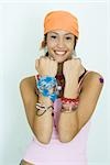 Teen girl wearing lots of accessories, holding up forearms, smiling at camera, portrait