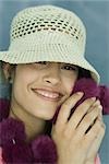 Teen girl wearing sun hat holding up fur scarf to face, close-up, portrait