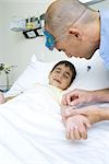 Boy lying in hospital bed, nurse adjusting IV