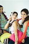 Three young female friends dressing up with scarves, one making face