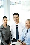 Three business associates standing together, smiling at camera