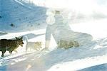 Adolescente, accroupi dans la neige avec deux chiens, vue arrière