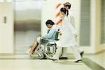 Personnel médical pousser un homme en fauteuil roulant, flou de mouvement