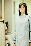 Young woman wearing hospital gown, looking away, hospital corridor in background