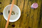 Fish bones on table next to bowl with chopsticks