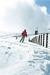 Mature man skiing down ski slope, full length