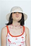 Teenage girl puckering lips at camera, wearing hat, portrait