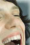 Cropped view of teenage boy laughing, eyes closed, extreme close-up