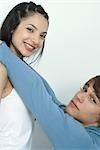 Young couple, man reaching up to put arms around woman's neck, portrait