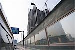 Wall on side of road, viewed from vehicle, high rise under construction in background