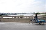 Cyclist with cart crossing bridge, blurred motion