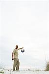 Man holding globe in plastic bag, looking at camera, mid-distance