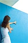 Woman holding on to wall, side view