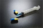 Syringe and drug capsules, close-up