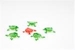 Green plastic frogs surrounding red frog in center