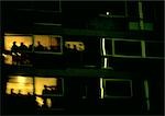 France, Paris, people silhouetted in apartment building at night