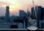 Glass with ice and straw in front of blurred cityscape