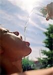 Woman pouring water into mouth under sun