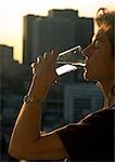 Woman drinking water, high rises in background