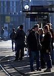 Group of people standing near tracks on corner of the block