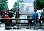 People standing at bus stop, rear view.