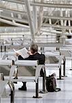 Businessman waiting in airport, reading newspaper