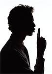 Man holding finger out in front of lips, silhouette.