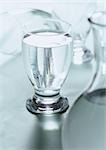 Glass of water with carafe blurred in foreground