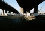 Road underneath bridges, train moving in background