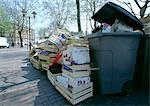 Empty boxes and crates piled up beside overflowing trash bin