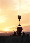 Silhouettes of workers near cement mixer at sunrise