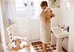 Woman taking bath, man with towel wrapped around waist shaving, in bathroom