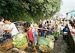 China, Sichuan, Chongqing, workers carrying yoked baskets of produce up steps leading from river boat dock