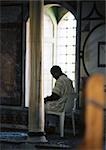 Israel, Jerusalem, person sitting in plastic chair in mosque, next to window