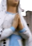 Statue de vierge avec les mains en prière, vue partielle, floue