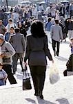 Woman walking in crowded street, rear view, blurred