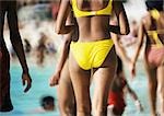 Woman wearing bikini on crowded beach, rear view, mid section
