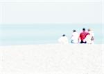 Gruppe von Menschen sitzen auf Sand am Strand, Rückansicht, verschwommen