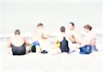 Gruppe von Menschen sitzen auf Sand am Strand, verschwommen