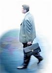 Homme d'affaires marchant avec porte-documents sur le globe, montage