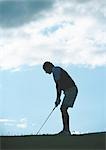 Golfer preparing to swing, backlit